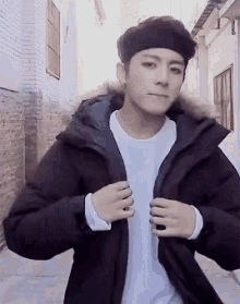 a young man wearing a black jacket with a fur hood