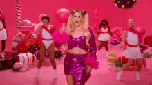 a woman in a pink dress is dancing in front of candy canes