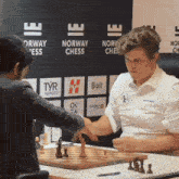 two men playing a game of chess in front of a norway chess sign