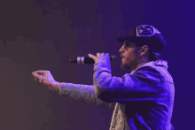 a man singing into a microphone while wearing a black hat