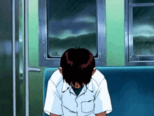 a man sits on a bench with his head down in front of a window