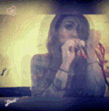 a woman with tattoos is singing into a microphone in front of a screen .
