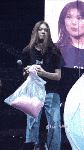 a woman holding a bag of pink cotton candy wearing a black shirt that says bini
