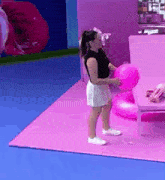 a woman is holding a pink balloon in a pink room .