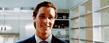 a man in a suit and tie is smiling in front of shelves
