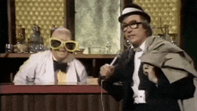 two men are standing next to each other in a bar talking on a microphone .