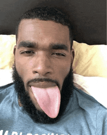 a man with a beard is sticking his tongue out while wearing a shirt that says arizona