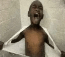 a shirtless young boy is taking a bath in a bathtub .