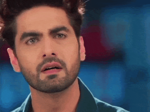 a close up of a man 's face with a beard and a blue shirt .