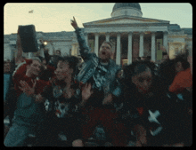 a crowd of people are dancing in front of a building with a dome and columns