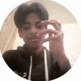 a young man wearing a black hoodie is taking a picture of himself