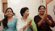 three women sitting next to each other clapping their hands in front of a coca cola bottle