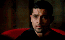 a close up of a man 's face with a red couch in the background