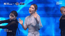 a woman in a white dress is dancing on a stage in front of a screen that says mnet