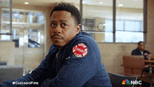 a man wearing a chicago fire jacket sits in a chair