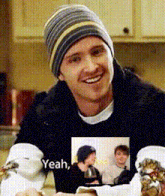 a man wearing a beanie and a black sweater says yeah