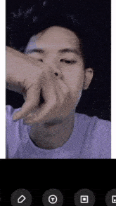 a man in a purple shirt is covering his nose with his hands
