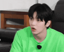 a young man wearing a green sweater is sitting in a chair .
