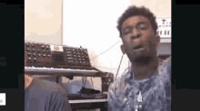 a man is singing into a microphone in front of a keyboard in a recording studio .