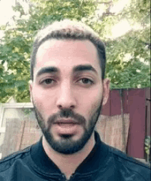 a man with a beard is wearing a black jacket .
