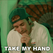 a man singing into a microphone with the words take my hand written below him