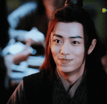 a young man with long hair is smiling for the camera