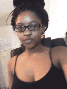 a woman wearing glasses and a black tank top taking a selfie