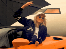 a woman wearing a jacket that says doy on it is sitting in an orange car