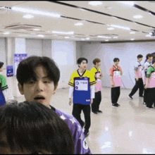 a group of young men are standing in a room and one of them is wearing a purple shirt with the number 9 on it