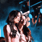 two women standing next to each other with one wearing a crown