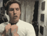 a man in a white shirt and tie is looking at himself in the mirror