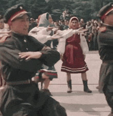 a group of people in military uniforms are dancing in front of a crowd of people .