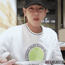 a man wearing a white shirt with a tennis ball on it and a black hat