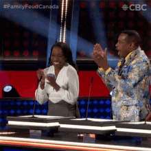 a man in a colorful suit and a woman in a white shirt are applauding .