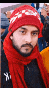 a man wearing a red beanie and a scarf with the letter k on it