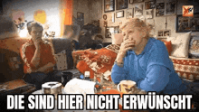 two elderly women are sitting at a table in a living room talking to each other .
