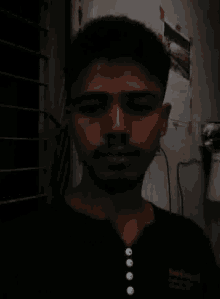 a man with a beard is taking a selfie in a dark room with a black shirt on .