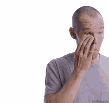 a man with a shaved head is touching his forehead with his hand