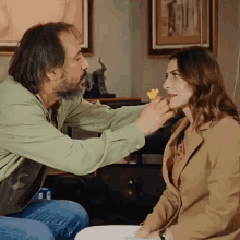 a man with a beard is putting a yellow object on a woman 's face