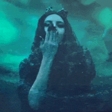 a woman in a black dress is blowing a kiss in a dark room .