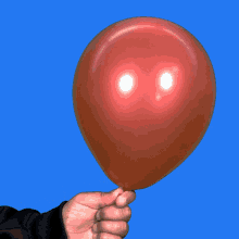 a person is holding a red balloon in their hand against a blue background