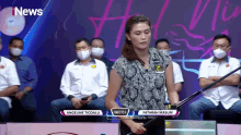 a woman is holding a badminton racket in front of a screen that says i news