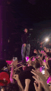 a man in a ny hat stands on a stage with a crowd behind him