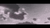 a black and white photo of a cloudy sky with a blurred background .