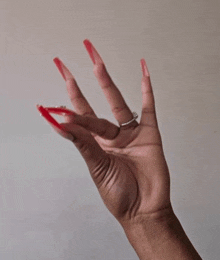 a woman 's hand with red nails and a diamond ring