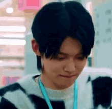 a close up of a person wearing a striped sweater and a lanyard .