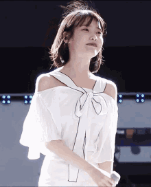 a woman wearing a white off the shoulder top with a black bow