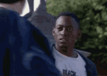 a man in a black shirt is standing in front of a statue and talking to another man .