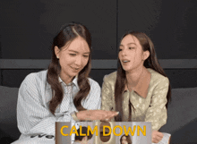 two women are looking at a magazine that says calm down on it