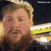 a man with a beard is standing in front of a waffle house sign